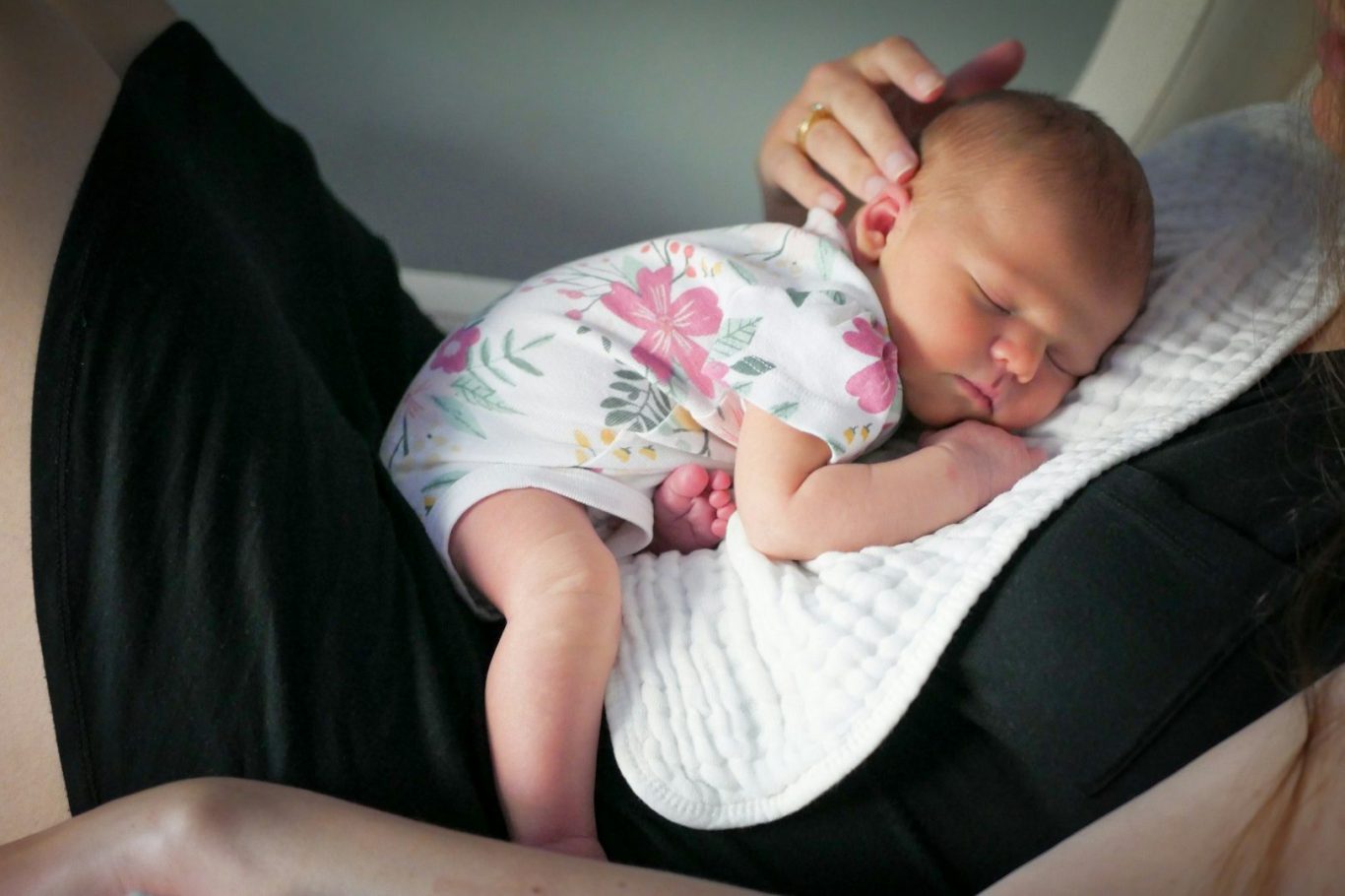 Schlafberatung.jpg Neugeborenes Baby schläft friedlich in den Armen einer Person.