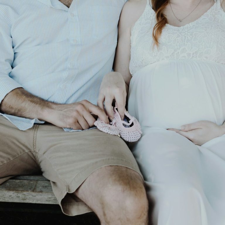 Schwanger.jpg Ein schwangere Frau und ein Mann halten rosa Babyschuhe zusammen.