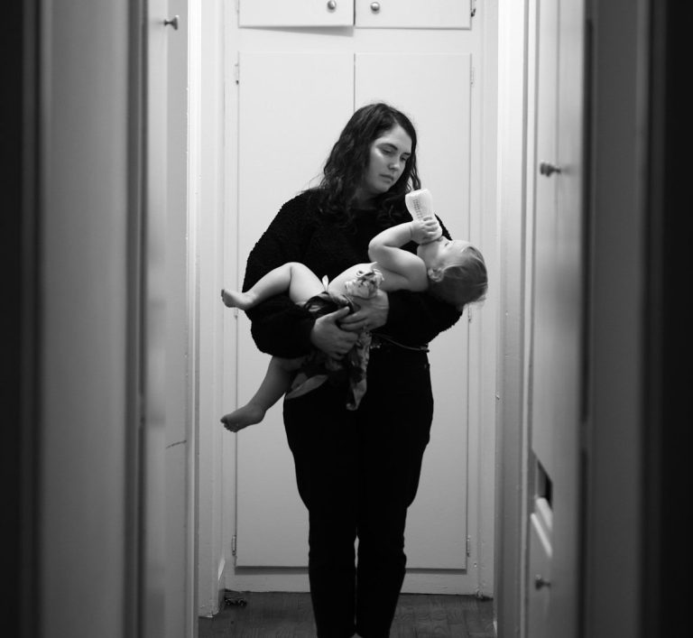 Formulaberatung.jpg Eine Person hält ein Baby in einem schmalen Flur.