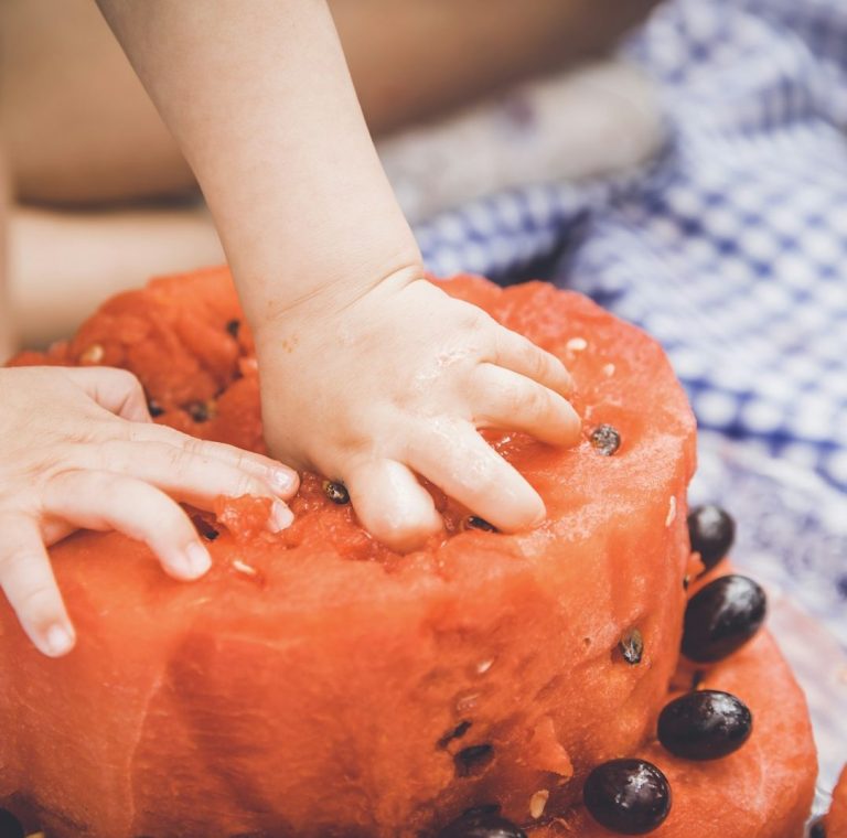 Beikostberatung.jpg Ein kleines Kind greift in ein Stück Wassermelone.
